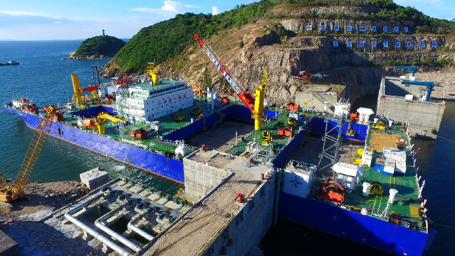 深中通道海底隧道部分是世界首例雙向八車道鋼殼海底沉管隧道，E2管節(jié)為首個標(biāo)準(zhǔn)管節(jié)，長165米，寬46米，高10.6米，重約7.7萬噸。比不久前完成安裝的E1管節(jié)比41.5米、重量超出2萬噸。標(biāo)準(zhǔn)管節(jié)E2在施工工藝、安裝條件等方面面臨多個“第一次”：為保證作業(yè)安全，中交集團(tuán)所屬中交一航局科研團(tuán)隊對E2管節(jié)與一體船的連接進(jìn)行重新核算。圖為施工現(xiàn)場。