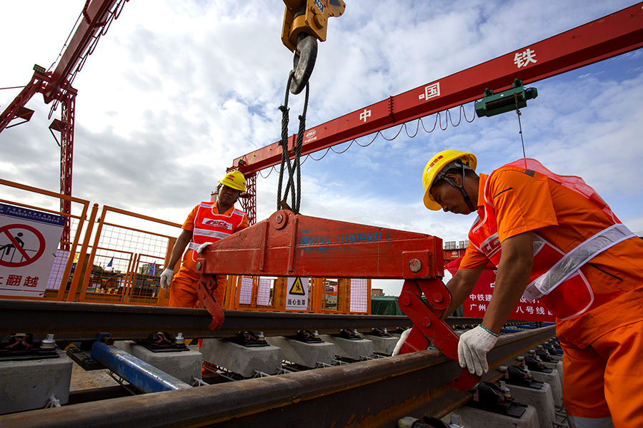 廣州地鐵十八號線線路全長61.3公里，起始于南沙萬頃沙樞紐，止于天河廣州東站，途徑南沙區、番禺區、海珠區及天河區，設9站8區間。其中，9座車站有8座車站為換乘站，最長站間距達25.9公里，為橫瀝至番禺廣場區間，這是目前國內站間距最大的地鐵區間。圖為作業人員正在掛軌排吊鉤。（彭特 攝）