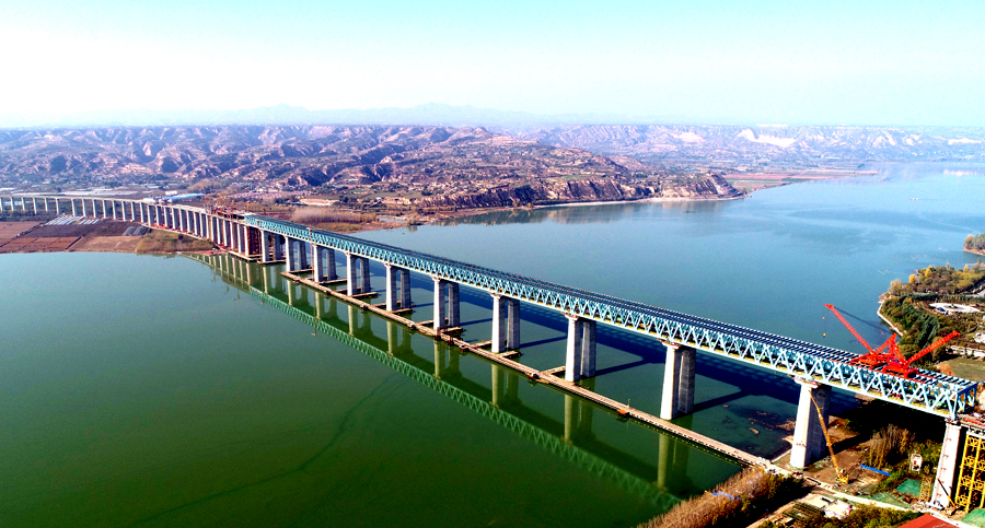 作為溝通“長江經(jīng)濟(jì)帶”與“絲綢之路經(jīng)濟(jì)帶”的重要干線，浩吉鐵路跨越數(shù)十條高速公路，穿越和連接20余條鐵路干線，第一次集疏運系統(tǒng)同步規(guī)劃和建設(shè)，銜接了沿線眾多煤炭基地和輸出入線路，豐富了這條能源大動脈的“毛細(xì)血管”，解決了鐵路運輸前后“一公里”難題。圖為中國鐵建大橋局承建浩吉鐵路三門峽黃河公鐵兩用大橋。