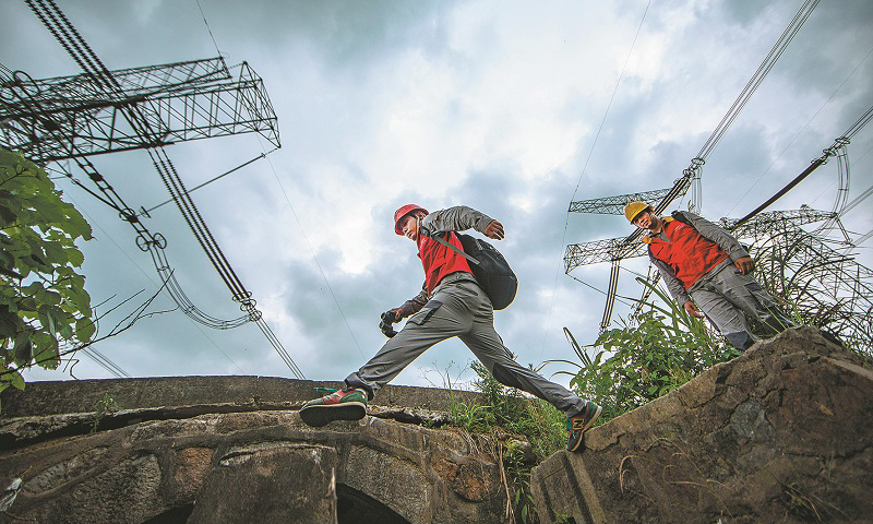 特高壓密集通道多處于山區，地理環境復雜，植被茂密，山火頻發，一旦發生線路同跳，將直接危及華東電網的安全。近日，天氣炎熱，用電負荷攀升，特高壓線路密集通道的運維也迎來了一年中最緊張的時期。圖為巡檢過程中，工作人員跨過山溝。