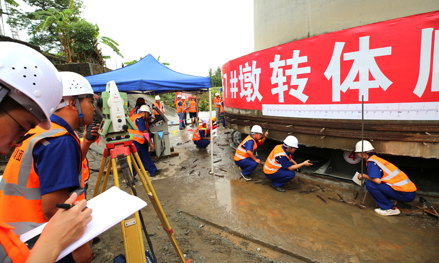 橋梁轉(zhuǎn)體的關(guān)鍵部件是直徑3.6米的圓盤形球鉸裝置。它下部與大橋的承臺緊密連接，上部是13層樓高、重量與1500頭大象相當(dāng)?shù)臉蛄骸Ｔ谵D(zhuǎn)體時，分列橋梁兩側(cè)的兩臺千斤頂，牽引鑲嵌在墩身承臺里的26根成人大拇指粗細的鋼絞線，大橋即可以每分鐘轉(zhuǎn)動近1度的速率緩緩轉(zhuǎn)動，直至轉(zhuǎn)體完成。圖為現(xiàn)場技術(shù)、安全人員全程認真盯控，確保大橋安全跨越老成昆鐵路。