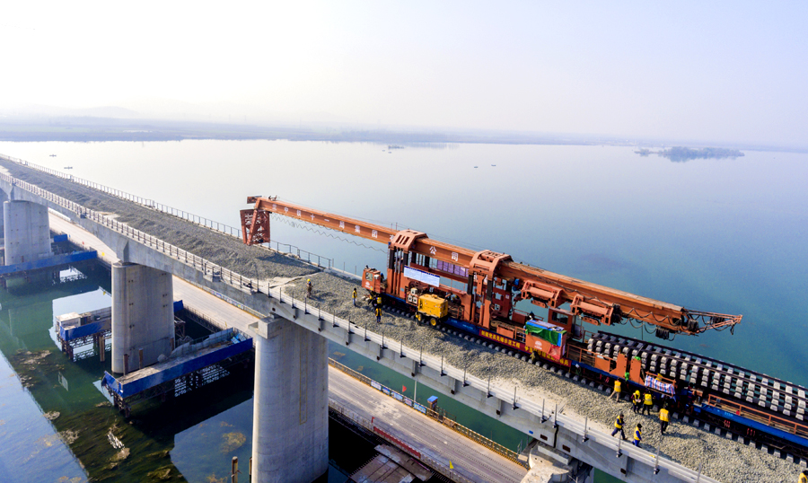 中鐵十九局蒙華鐵路鋪架4標建設者使用CPG500型鋪軌機，并結合采用單枕連續(xù)作業(yè)、長鋼軌鋪設和軌枕布設同步進行等方式，提高施工作業(yè)效率。中鐵十一局在傳統(tǒng)重載梁鋪架的基礎上進行技術創(chuàng)新，首次采用便于安裝拆除檢修的IIFC16型軌枕等諸多全新技術和工藝，確保線路質量和鋪軌安全。圖為蒙華鐵路湖北段鋪軌過漢江。