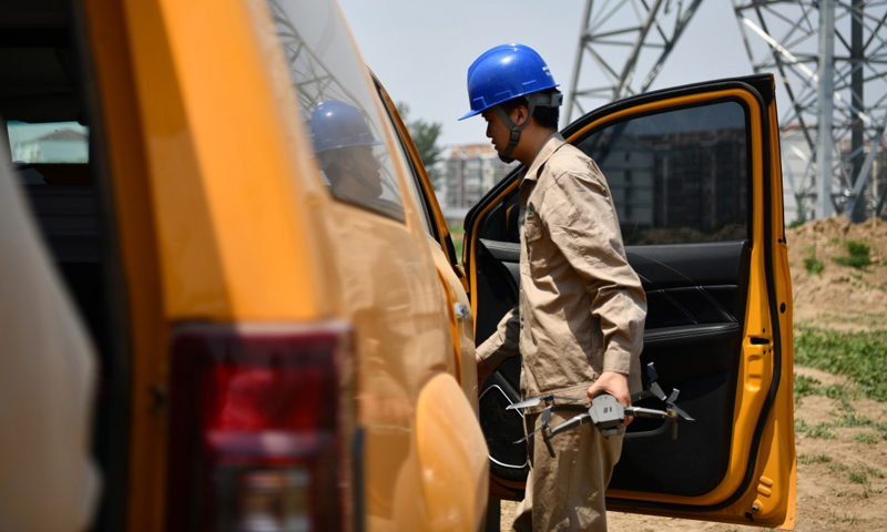 圖為6月24日，電力工人從車上取出無人機(jī)準(zhǔn)備開始巡檢工作。（新華社記者 李然 攝）