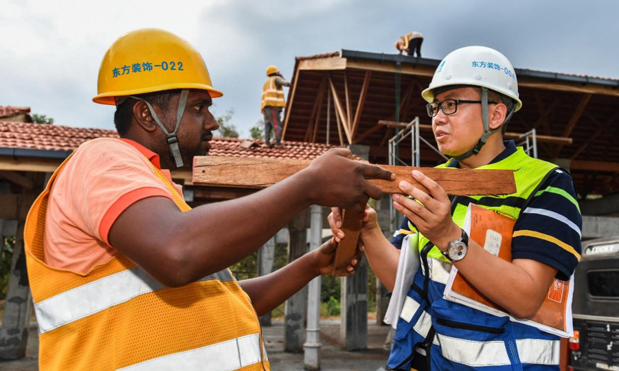 胥超(右)給當(dāng)?shù)毓と说呢?fù)責(zé)人講解木結(jié)構(gòu)的構(gòu)造原理。