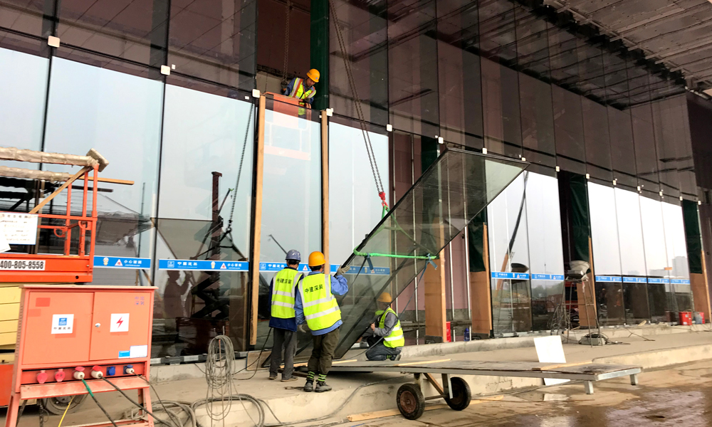 整個會議中心由鋼結構支撐，鋼結構外面全包裹著玻璃幕墻，8千余塊玻璃均為“量身定做”，有獨立編號。圖為4月13日，中建裝飾建筑工人正在吊裝FS2底層坐式全玻幕墻。（國務院國資委網站 李子紅 攝）