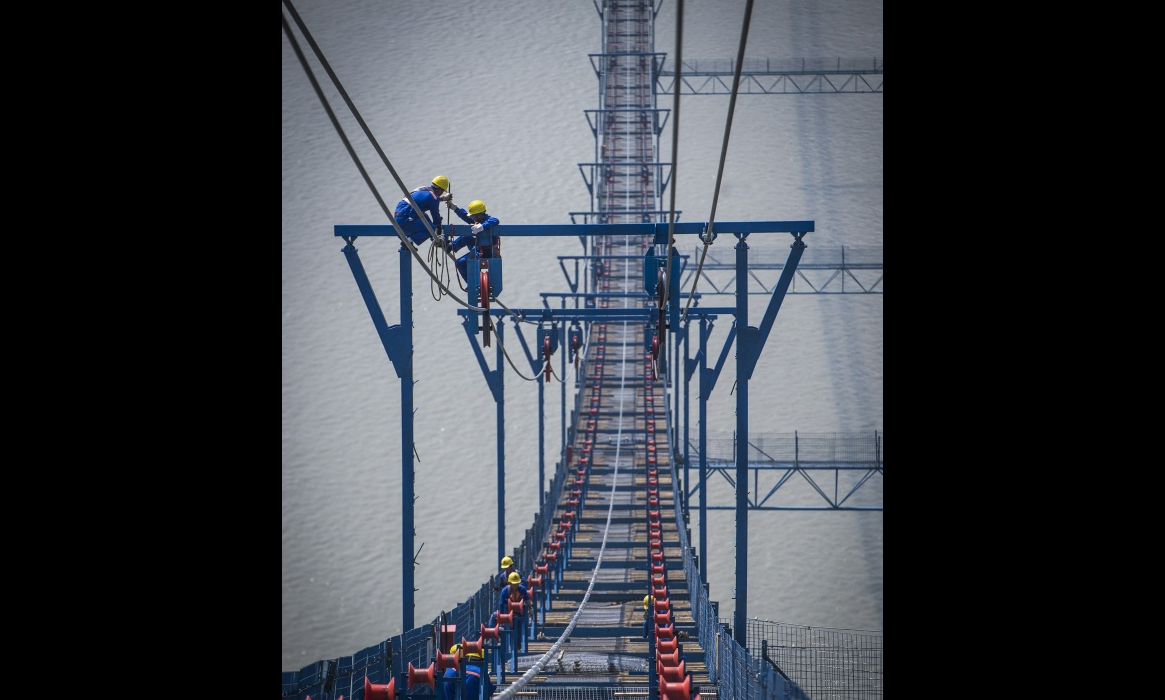 6月10日，工人在高空中架設主纜。（新華社記者 肖藝九 攝）
