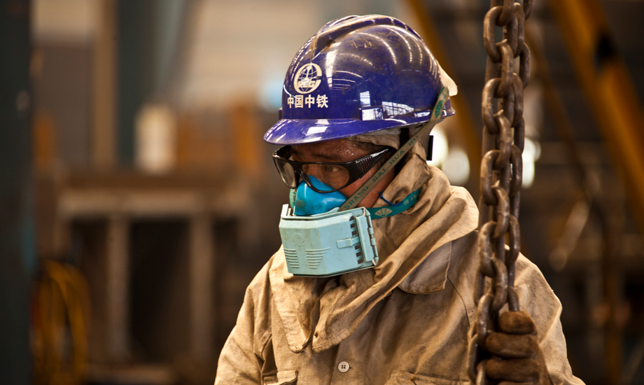 盡管室外氣溫已達38攝氏度，因為安全防護需要，中鐵四局鋼結構建筑公司制造分公司的作業工人也必須把自己從頭到腳防護起來。汗水從帽子和眼鏡的縫隙里流淌下來。每個工位都有不停轉的風扇，每個工人都有超大容量的水杯。每年他們都要經歷百十來個這樣難熬的高溫工作日。（作者：朱曉晨）