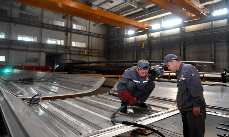 4月27日，周晶輝（右）與徒弟臧鐵軍一起研究改進高鐵車體焊接工藝。（新華社記者 張楠 攝）