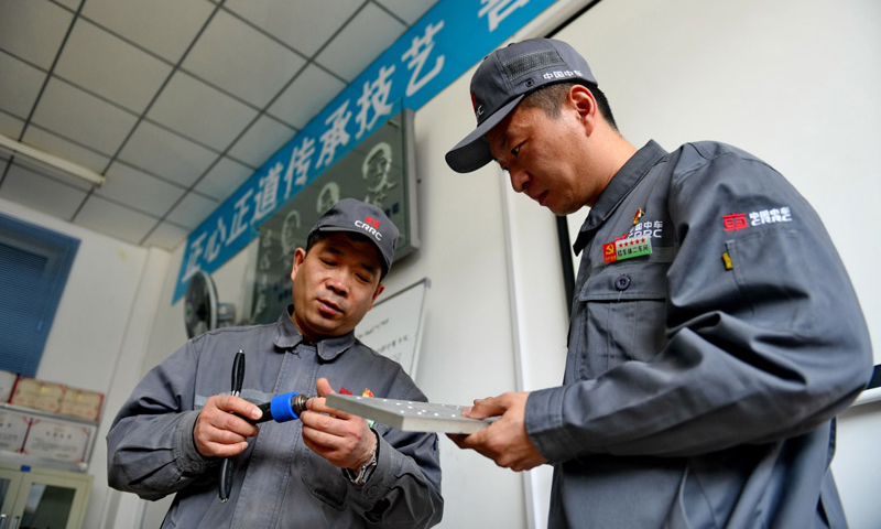 4月27日，周晶輝（左）與徒弟臧鐵軍一起研究改進工作中使用的工具。（新華社記者 張楠 攝）