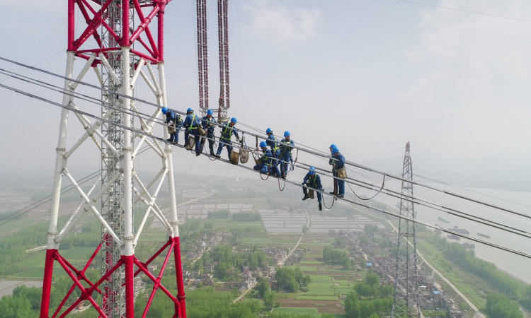 4月15日，在安徽省無為縣高溝鎮，工人們在昌古特高壓長江大跨越工程跨越塔導線上進行高空作業（無人機拍攝）。