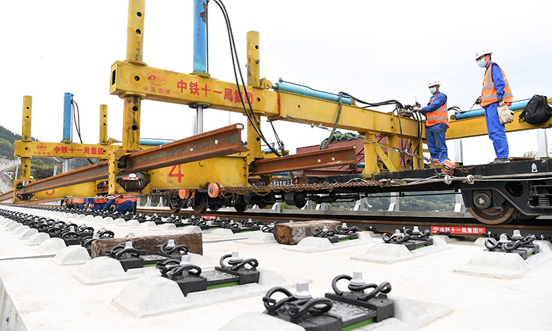 據了解，這次鄭萬高鐵重慶段鋪軌，首次運用了BLCP500型本鄰兩線長軌鋪設機組，在第一條線路鋪設完成、不需要中轉的情況下，對鄰線進行長軌鋪設，省去了換線鋪軌牽引車折返時間，減少了調車作業的次數，鋪軌準備時間減少約50%，大幅提升了鋪軌作業效率。圖為3月17日，BLCP500型本鄰兩線長軌鋪設機組進行機械化跨線鋪軌作業。（新華社記者 唐奕 攝）