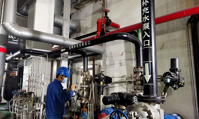 圖為華能鶴崗電廠檢修部員工在供熱首站巡視設(shè)備運行情況。
