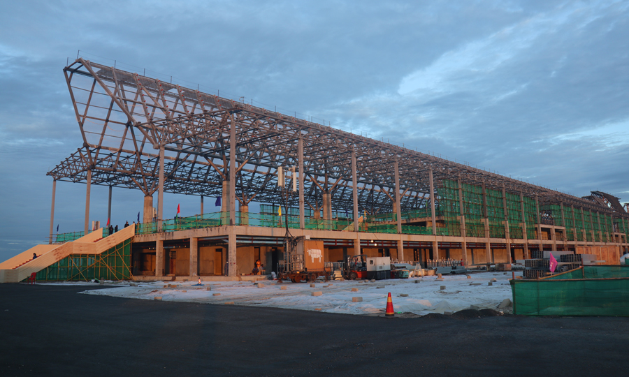 暹粒吳哥國際機(jī)場(chǎng)項(xiàng)目飛行區(qū)跑道長3600米、寬45米，是飛行區(qū)的主體工程。跑道混凝土工程自今年1月16日正式啟動(dòng)以來，克服疫情、高溫、降雨、地材緊張、海運(yùn)周期長等不利因素影響，積極引進(jìn)滑模攤鋪機(jī)施工，顯著提升了道面混凝土的施工質(zhì)量和效率，歷時(shí)125天，完成7萬立方米的混凝土澆筑，提前10天完成節(jié)點(diǎn)任務(wù)。圖為機(jī)場(chǎng)航站樓項(xiàng)目施工現(xiàn)場(chǎng)。