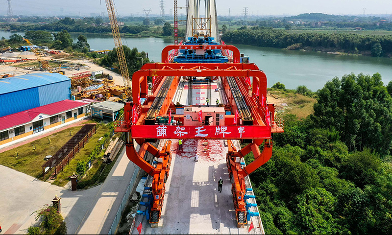 10月25日，施工人員操作架橋機將最后一孔900噸箱梁成功架設在增江特大橋橋墩上（無人機照片）。新華社記者 劉大偉 攝