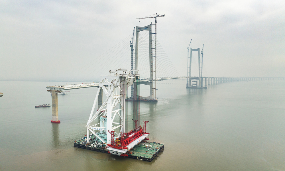 面對項目海域箱梁架設具有運輸線路長、穿越航道多、箱梁噸位重，架設精度要求高等難點，中鐵大橋局采用國內首創單體船型結構、全電力推進的海上架梁施工專用起重船“天一號”開展架設施工。圖為11月10日拍攝的深中通道施工現場。