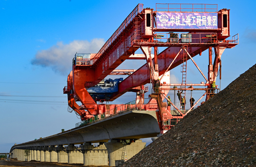 跨萬甘鐵路特大橋全長2526.8米，共有78孔預(yù)制箱梁，最大縱坡20‰，運(yùn)架梁施工過程上跨鐵路且鄰近鐵路營業(yè)線，屬于重大危險(xiǎn)源管控項(xiàng)目，是包銀高鐵項(xiàng)目重點(diǎn)控制性工程。項(xiàng)目部精心研究制定了運(yùn)梁、架橋機(jī)過孔、架梁專項(xiàng)管理措施和施工方案，全程嚴(yán)格盯控架梁施工環(huán)節(jié)，充分保障了架梁施工安全、質(zhì)量和進(jìn)度。圖為包銀高鐵跨萬甘鐵路特大橋箱梁架設(shè)施工現(xiàn)場(chǎng)。