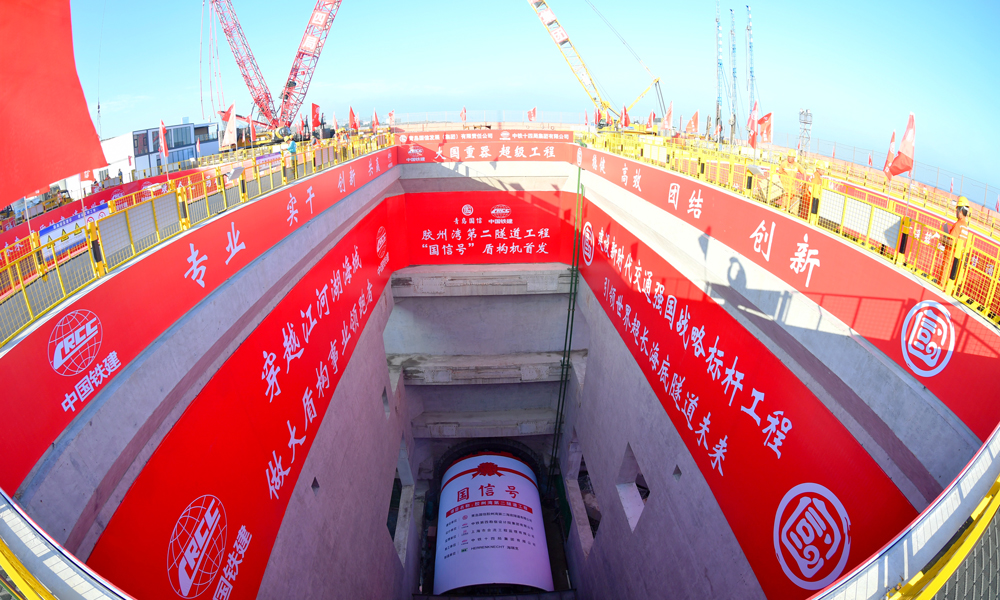 6月30日，膠州灣第二隧道“國信號”盾構(gòu)機(jī)在青島港8號碼頭順利首發(fā)，標(biāo)志著由青島國信集團(tuán)投資建設(shè)，中國鐵建所屬鐵四院設(shè)計(jì)、中鐵十四局施工的世界最長海底道路隧道——膠州灣第二隧道工程盾構(gòu)段正式掘進(jìn)施工，開啟了膠州灣東西兩岸“對向掘進(jìn)”的跨海征途。圖為膠州灣第二隧道“國信號”盾構(gòu)機(jī)始發(fā)現(xiàn)場。