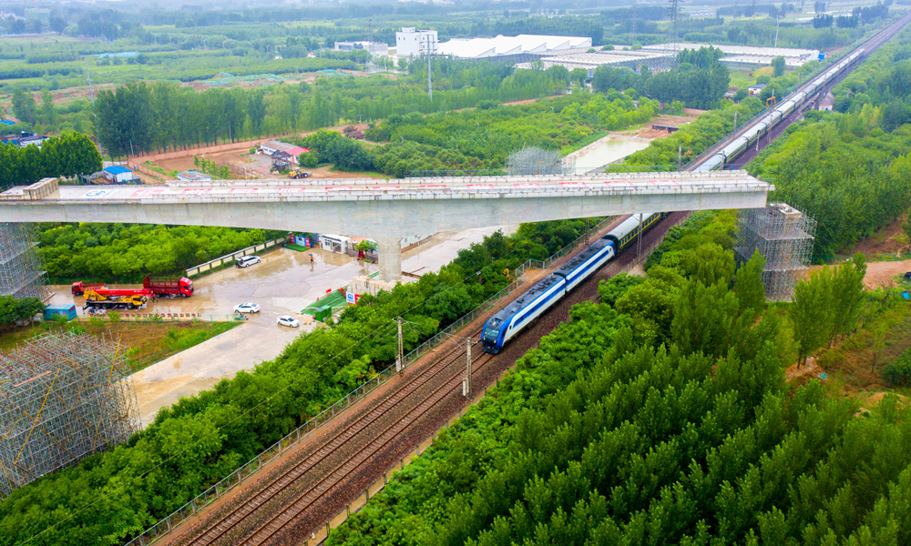 近日，中國中鐵旗下中鐵四局承建的雄安新區至北京大興國際機場快線跨京九鐵路轉體梁順利合龍，為全線按期通車運營奠定了堅實基礎。圖為跨京九鐵路轉體梁轉體后火車經過轉體橋。