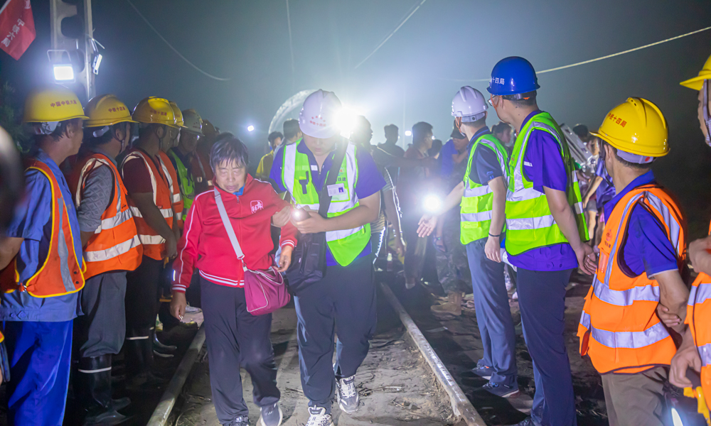 8月2日19時，中鐵十四局京唐項目、北京地鐵17號線項目80余名工作人員兵分兩路，一部分工作人員搬運枕木，重修鐵路路基；另一部分工作人員背靠坍塌部分路基，形成愛心人墻，協助被困Z180列車503名乘客解除困境。侯慧 攝