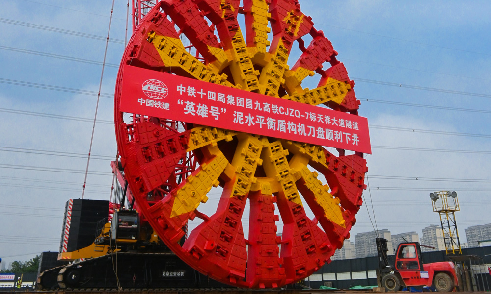 日前，在中國鐵建所屬中鐵十四局昌九高鐵天祥大道隧道施工現(xiàn)場，國產(chǎn)最大直徑高鐵隧道盾構機“英雄號”開始吊裝下井進行組裝。圖為“英雄號”盾構機下井組裝。
