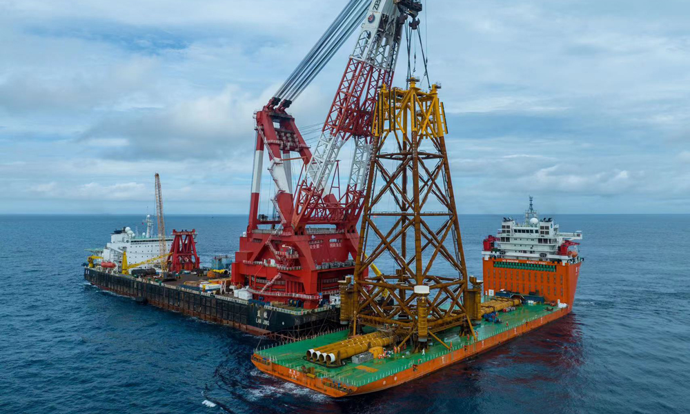 如何在短時間內將觀測平臺精準安裝至設計坐標點位，對吊裝操作和現場指揮提出嚴峻挑戰。針對觀測平臺結構特點以及安裝海域復雜的水動力環境，項目團隊調配了亞洲頂級的海洋工程船舶 ——“藍鯨”號現場施工。面對吊裝重量達2080噸、高度達77.7米的導管架，采取“垂直起吊、垂直下放”的超高空作業方式，僅用半天時間就完成吊裝下水并精準就位。圖為“藍鯨”號完成觀測平臺導管架掛扣。