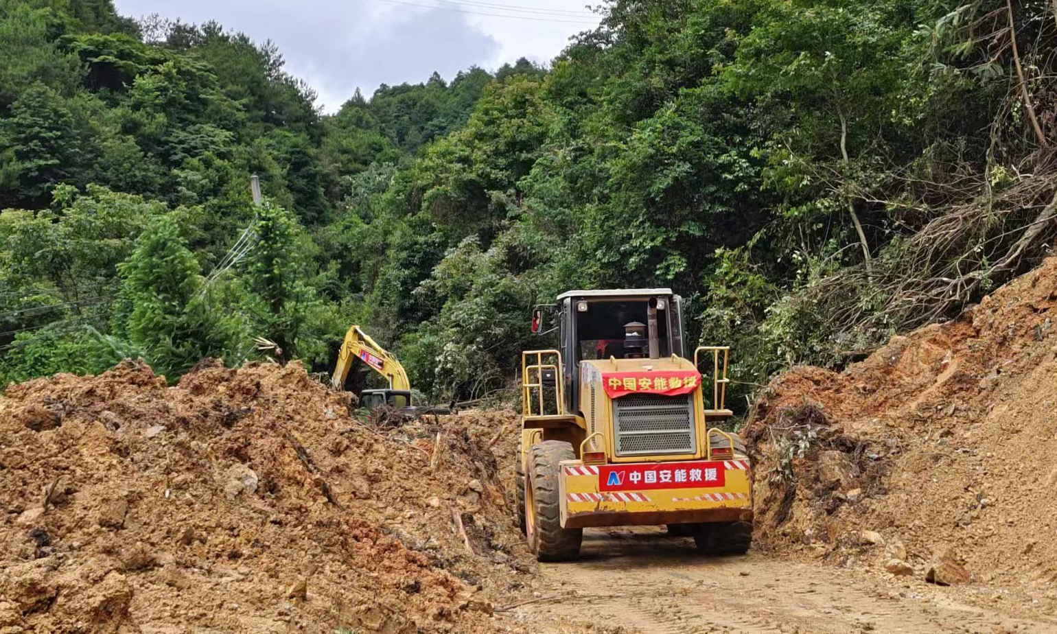 6月16日，廣東省梅州多地出現大暴雨局部特大暴雨，其中，平遠縣泗水鎮出現道路、通信、供電、供水中斷情況，多處發生山洪、山體滑坡、人員受困，梅州市已啟動防汛Ⅰ級應急響應。根據相關部門要求，中國安能二局從南昌、廈門、深圳等方向共抽組111人專業力量、30臺（套）救援裝備，于6月17日20時緊急趕赴災區，主要受領平遠縣上舉鎮S239線、通往平遠縣泗水鎮X038線2個方向道路搶通任務。圖為X038道路搶通現場。