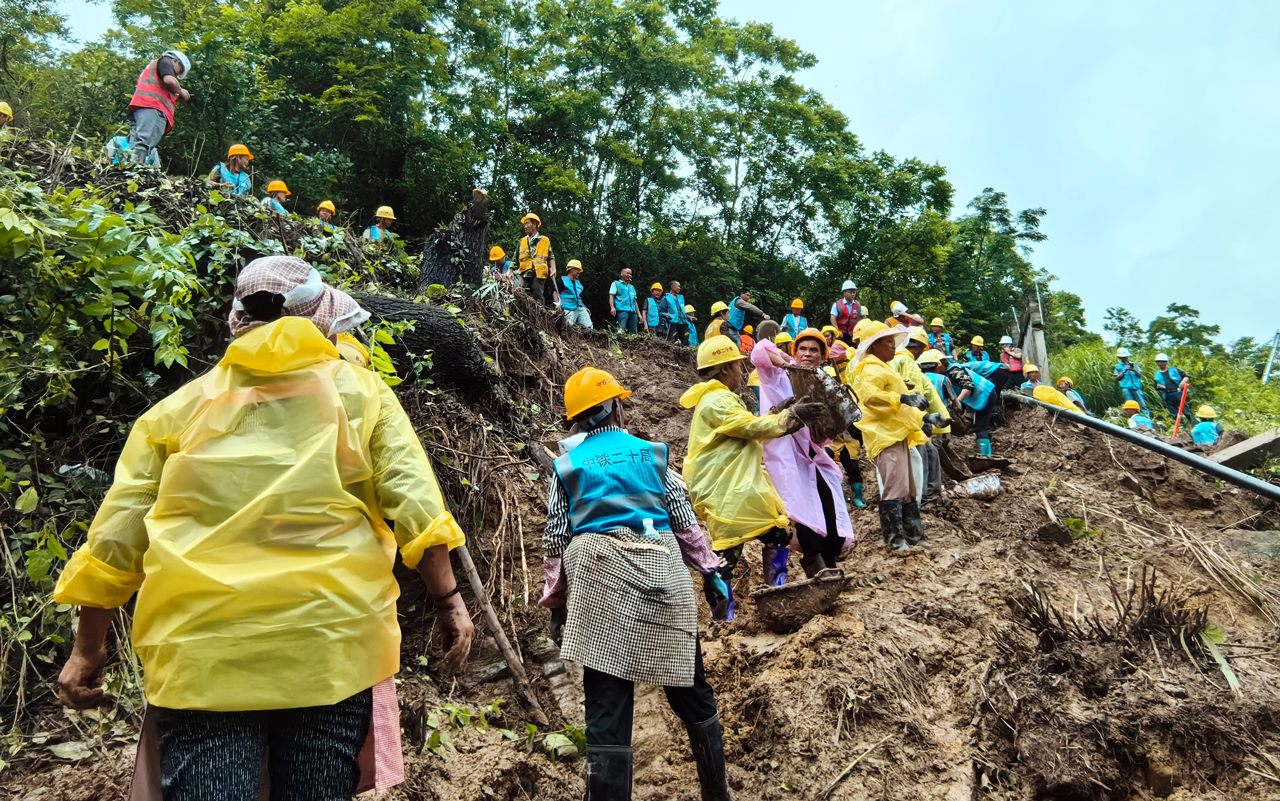 近日，貴州遵義出現今年以來首次特大暴雨。6月17日，播州區三合鎮木瑤堰村的渝貴高鐵（客專）黑石臺隧道右側出現因強降雨引發的險情，將可能造成滑坡、泥石流等次生衍生災害。中鐵二十局貴州公司甕馬鐵路十標項目組織搶險人員和物資、設備火速趕往現場。因搶險現場機械無法抵達，搶險人員肩扛手抬，冒雨展開搶險工作。截至目前，該項目累計投入450余人，運輸車輛70余輛，搶險64個小時，移除260余方坍塌土方，修筑51米臨時截水溝，搭設了32米排架，為鐵路正常通行保駕護航。圖為救援人員正在清理塌方淤泥。