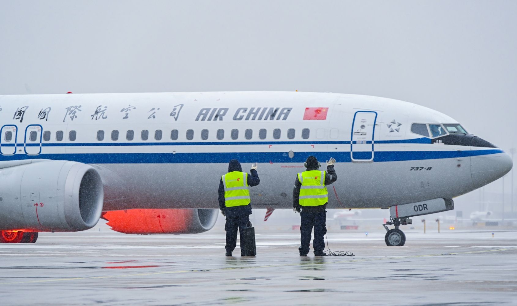 在北京首都國際機場，中航集團一線工作人員目送完成除冰雪作業的飛機緩緩出港。