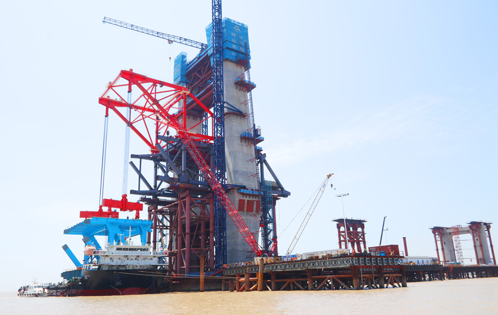 近日，中國(guó)中鐵旗下中鐵大橋局承建的滬渝蓉高鐵崇啟公鐵長(zhǎng)江大橋主通航孔橋首吊鋼梁架設(shè)完成。崇啟公鐵長(zhǎng)江大橋主通航孔橋?yàn)殡p塔雙索面鋼桁結(jié)合梁斜拉橋，主跨400米，孔跨布置總長(zhǎng)992米，是世界最大跨度雙塔雙索面公鐵兩用無砟軌道斜拉橋。主通航孔鋼桁梁共有80個(gè)節(jié)間，包含不同類型的節(jié)間分布及拼裝方式，總重量為36335噸。此次架設(shè)為上海側(cè)首吊A01A02節(jié)段，首吊總重891.8噸。橋面總寬37.2米。