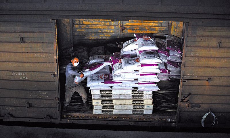 圖為裝卸工將優(yōu)質(zhì)化肥裝滿一節(jié)節(jié)車廂，準(zhǔn)備發(fā)往全國(guó)各地。