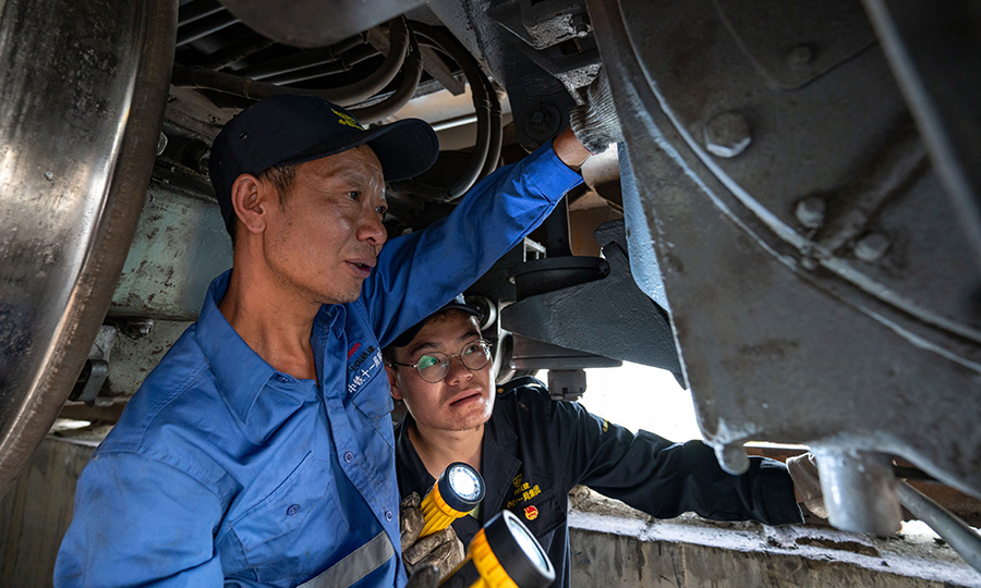 中鐵十一局集團作為拉林鐵路唯一的鋪架單位，承擔著全線的鋪軌任務，10余臺大型運輸設備晝夜不息的奔波在各個工點上，高強度的運輸作業(yè)，維保任務成了重中之重，檢修班組通過利用火車空車回基地裝卸貨的間隙，進行全面維保作業(yè)，自上場以來該班組已經維保800余車次，排除安全隱患50余次，期間未發(fā)生過1起運輸安全事故。圖為師傅帶徒弟檢查電機是否有拉傷。（丁慶濱 攝）