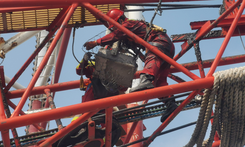 圖為在第19號(hào)臺(tái)風(fēng)“天鵝”來(lái)臨前，“COSLCRAFT”鉆井平臺(tái)電氣師正在對(duì)吊車扒桿照明燈進(jìn)行加固。