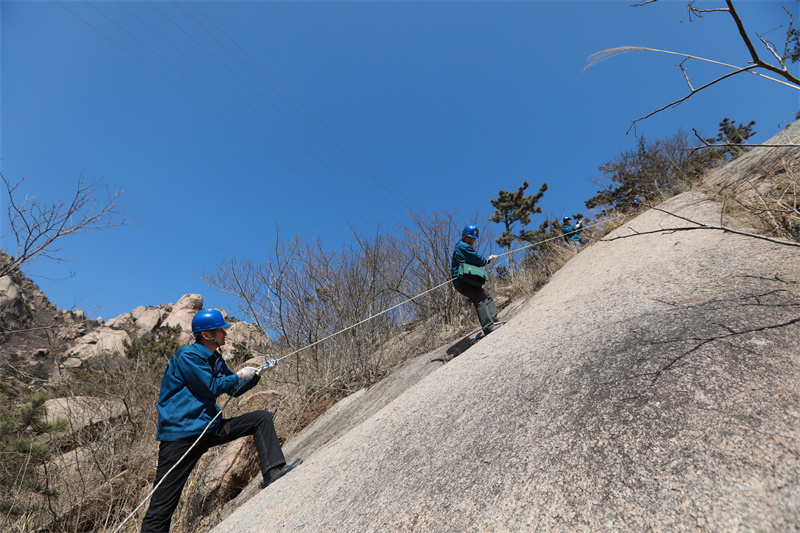 3月16日,山東榮成市供電公司員工對槎山上的電力線路進行特巡。坡度較大的山坡,巡檢人員需要借助繩子上下。.jpg 3月16日,山東榮成市供電公司員工對槎山上的電力線路進行特巡。坡度較大的山坡,巡檢人員需要借助繩子上下。.jpg